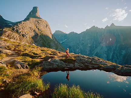 Frau läuft durch die Alpen an einem See vorbei.