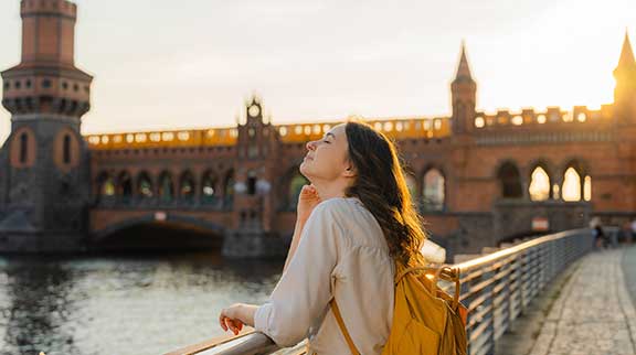 Frau schaut auf Gebäude und Fluss in Berlin.