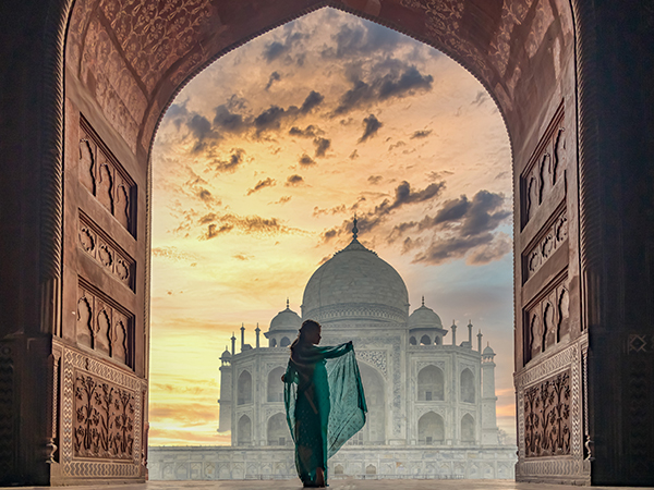 Frau im Sari steht vor dem Taj Mahal.