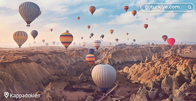 Heißluftballons fliegen über die Felsenlandschaft Kappadokiens.