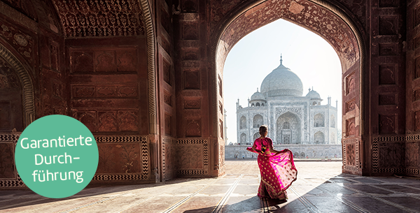 Frau steht im pinken Sari vor dem Taj Mahal.