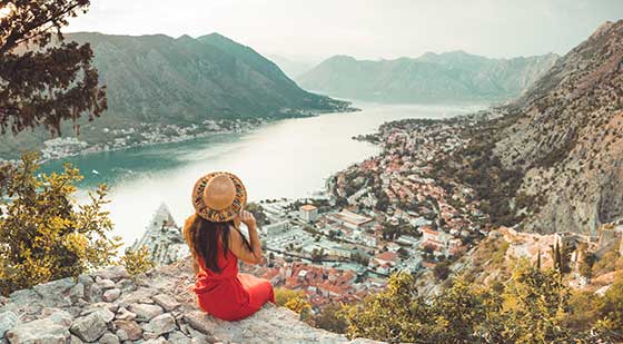 Frau schaut von einem Berg aus auf die Stadt Kotor.
