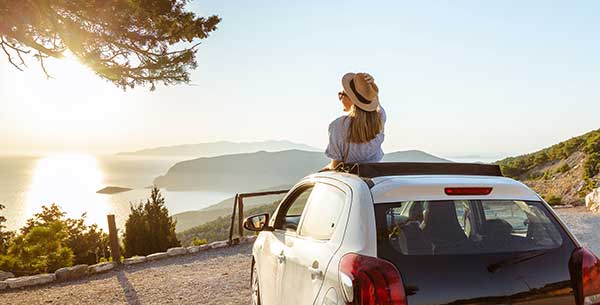 Frau schaut aus dem Auto auf die Küste mit Meer.