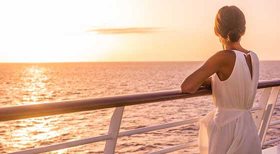 Frau blickt vom Schiff auf das Meer.