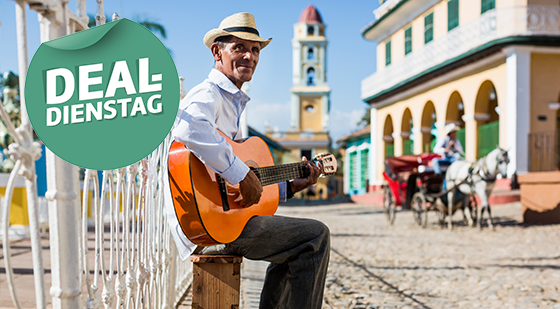 Ein Mann, der in einer Straße von Trinidad steht und auf einer Gitarre spielt.