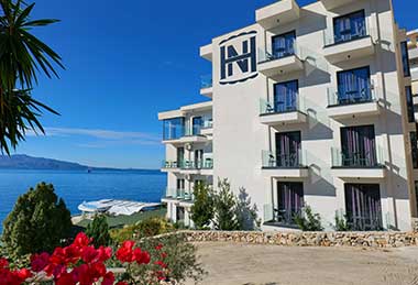 Außenansicht des Hotels mit Meer im Hintergrund.