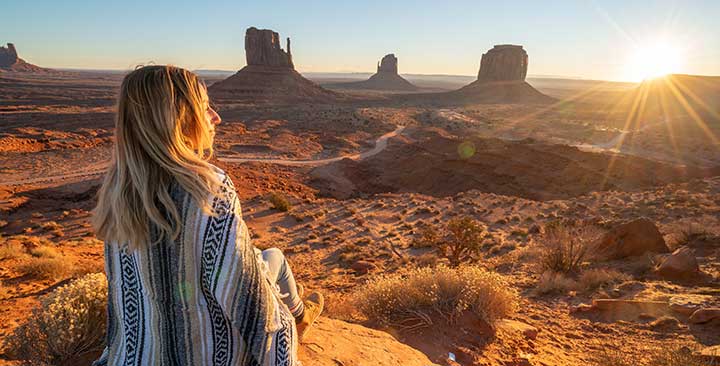 Frau schaut auf die Landschaft des Monument Valley bei Sonnenuntergang.