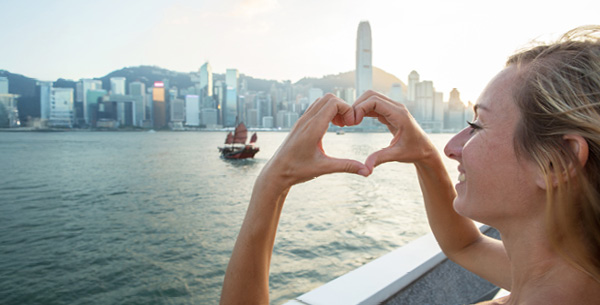 Frau bildet Herz vor der Hong Kong Sykline