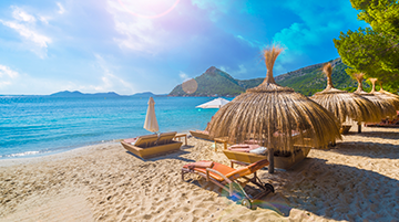 Sonnenliegen und Sonnenschirme an einem Sandstrand.