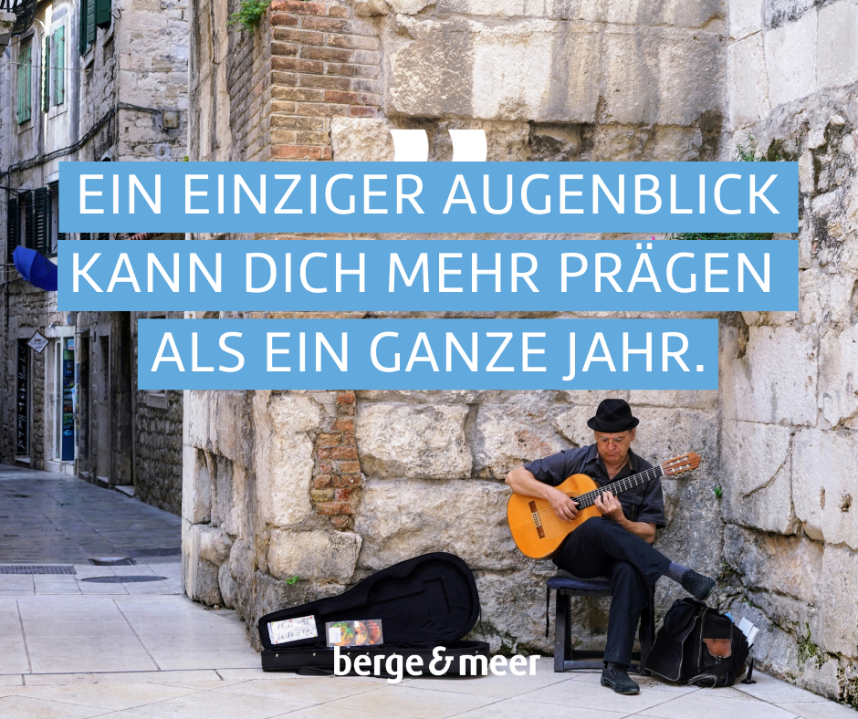 Straßenmusiker mit Gitarre an einer Hauswand