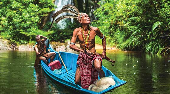 Zwei Einheimische in einem Boot im Dschungel in Malaysia.