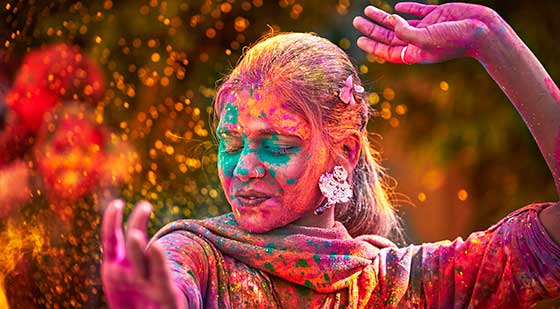 Inderin zum Holi-Fest umgeben von bunten Farben.