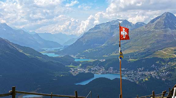 Schweizer Fahne weht vor Bergpanorama.