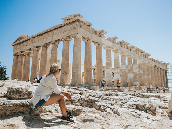 Frau sitz auf Steinen vor der Akropolis in Athen.