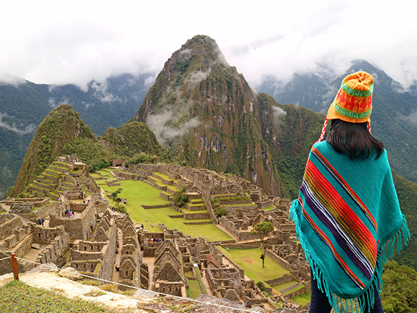 Frau blickt auf die Ruinen von Machu Picchu.
