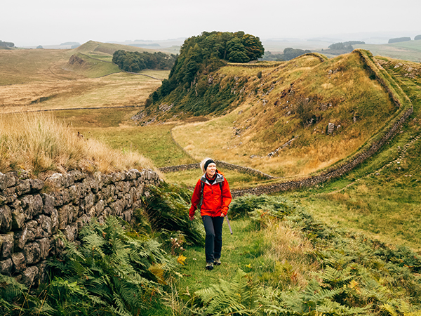 Frau läuft entlang der Hadrianswalls.