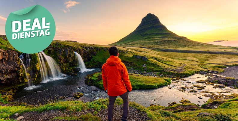Mann in roter Jacke blickt auf Landschaft von Kirkjufell mit Bergen und Wasserfall.
